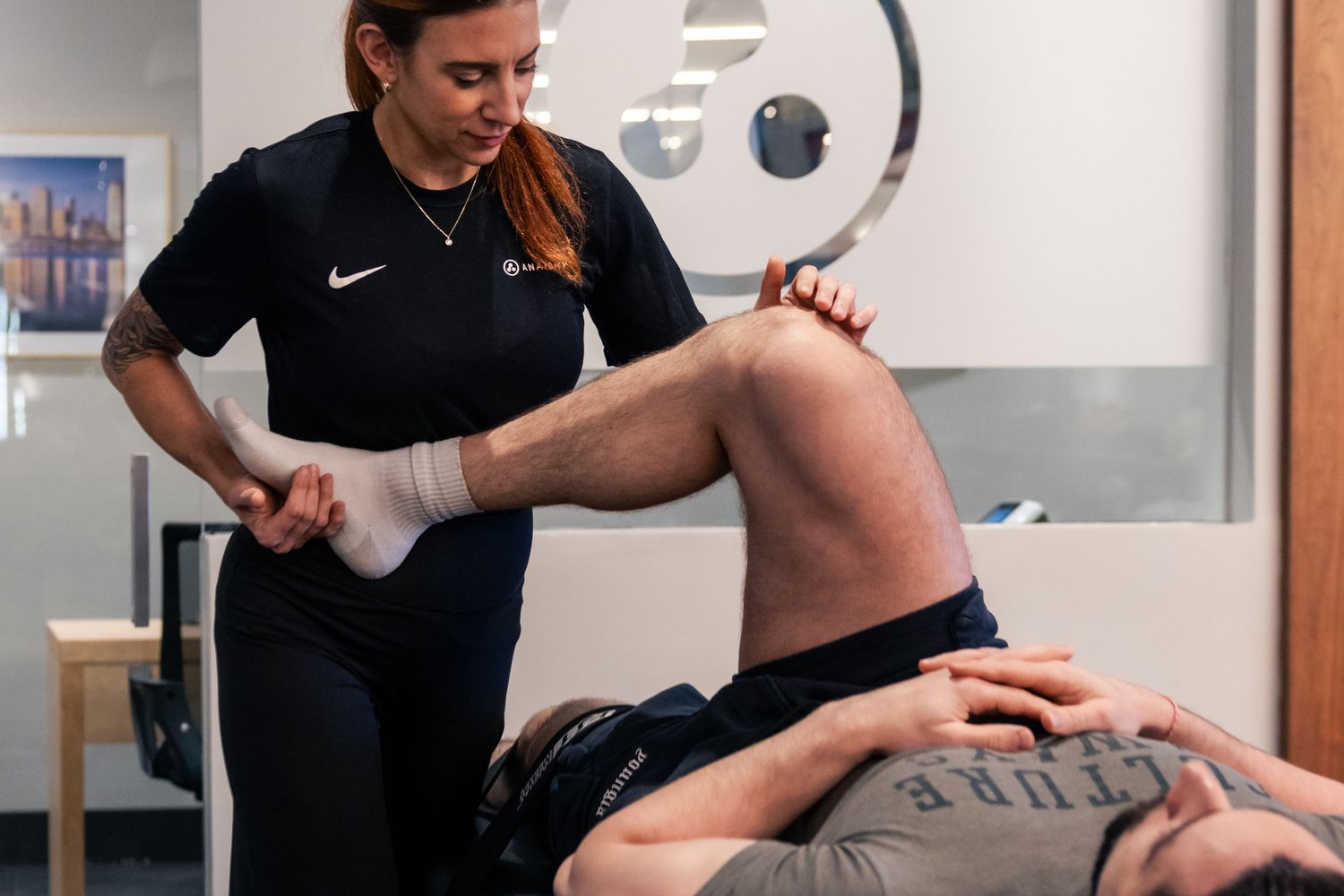 Anatomy coach performing an assisted hamstring stretch
